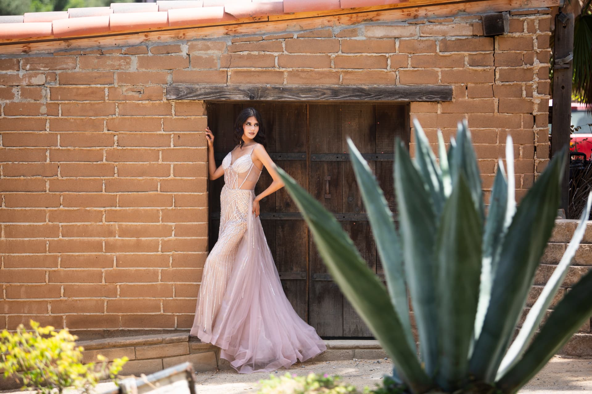 Wide editorial portrait of a model before a historic adobe building